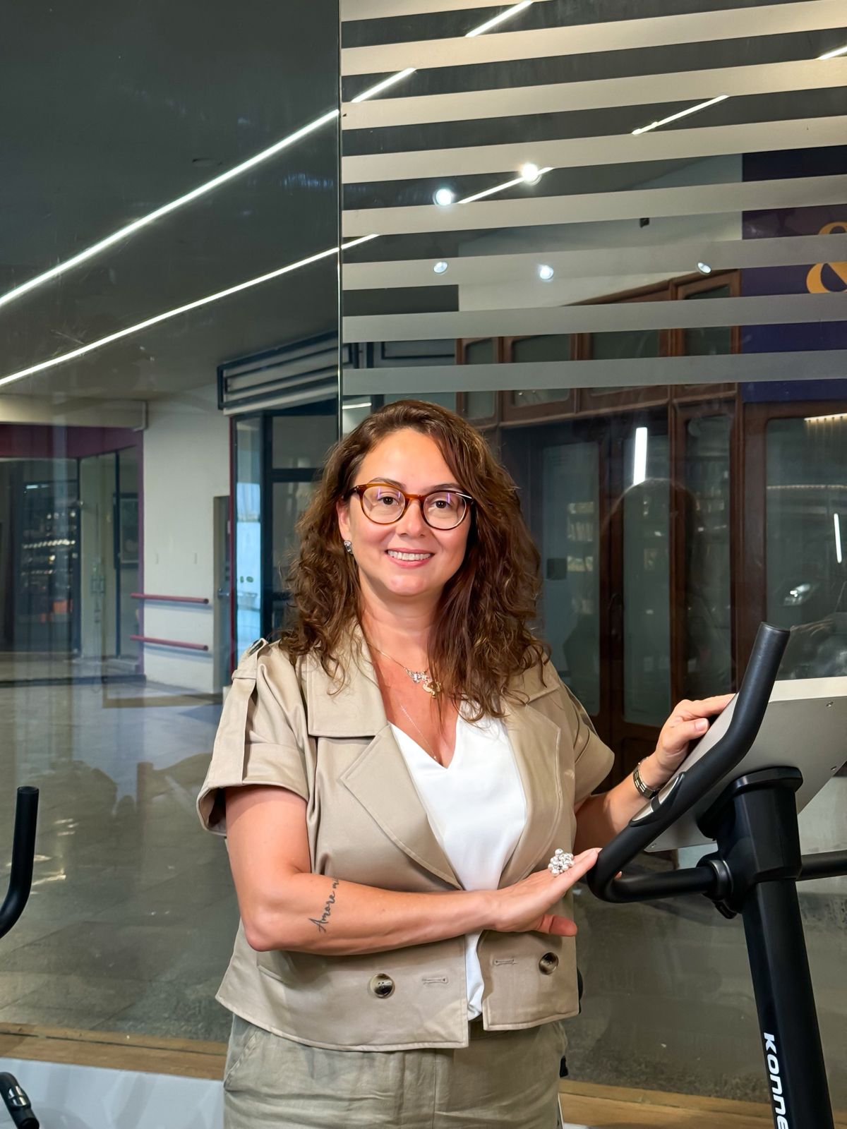 imagem da Dra Bruna Bacchini ao lado de uma bicicleta ergométrica