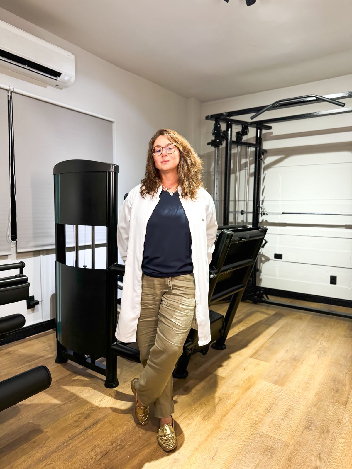 Dra Bruna Bacchini em pé em seu estúdio de fisioterapia respiratória